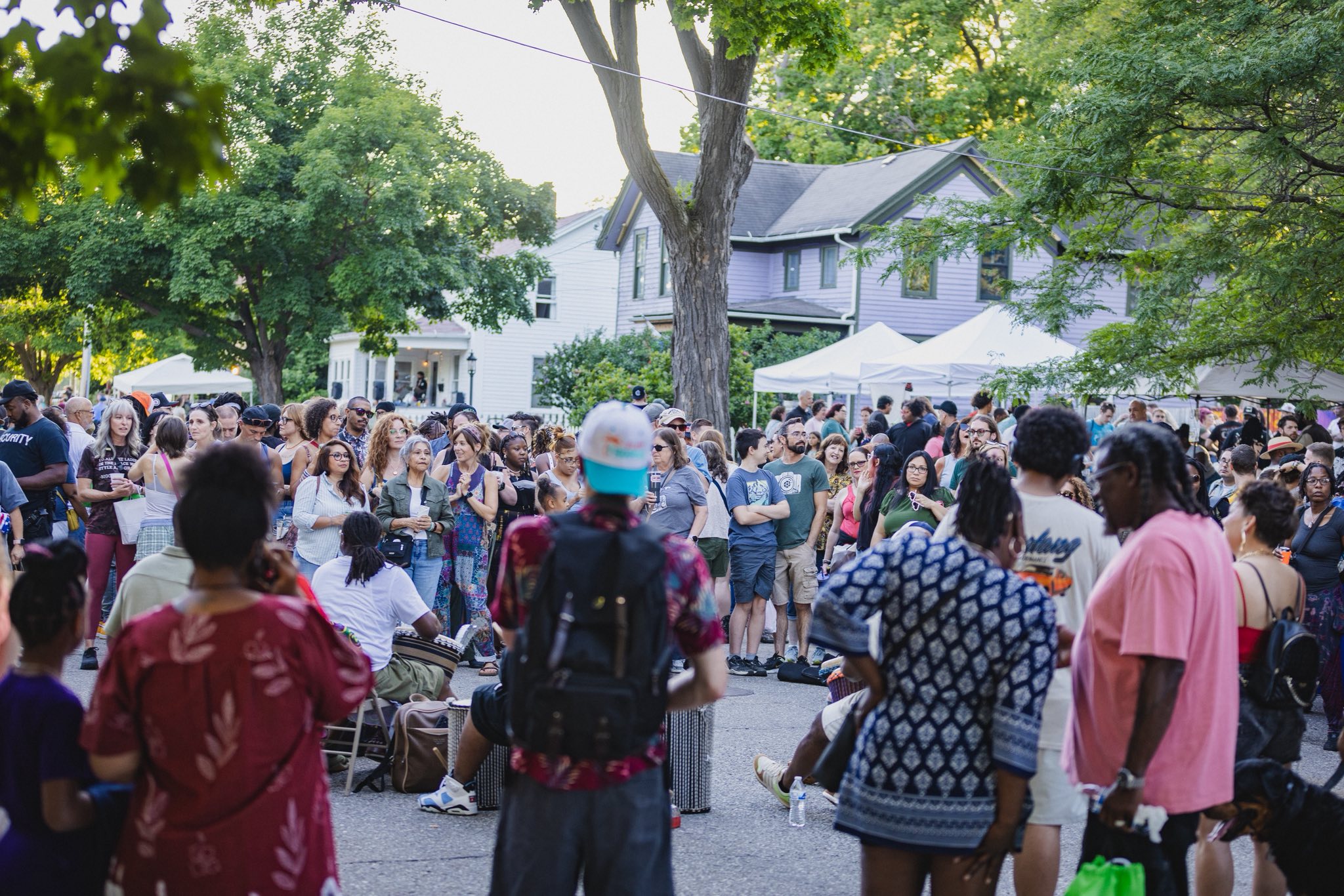 Wide view of hundreds at Porchfest with historic houses and vendor tents